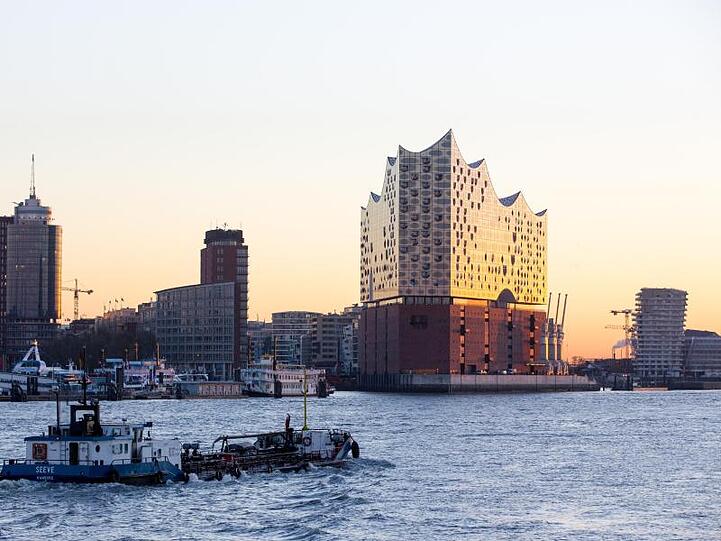 Die Elbphilharmonie leuchtet in der aufgehenden Sonne.