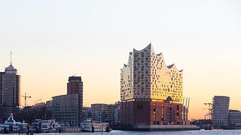 Die Elbphilharmonie leuchtet in der aufgehenden Sonne.