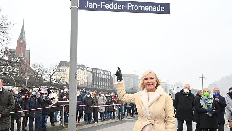 Witwe Marion Fedder unter dem neuen Straßenschild der Jan-Fedder-Promenade.