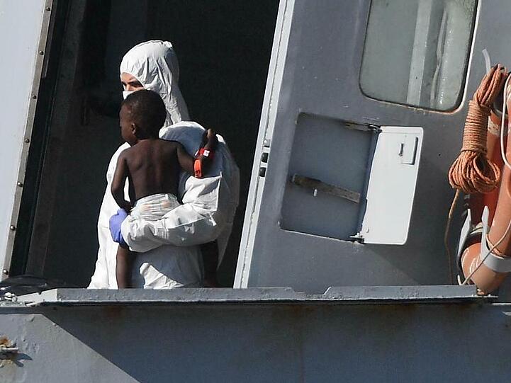 Ein Helfer bringt ein kleines Kind in Genua an Land: Leben retten soll in Italien künftig mit hohen Geldstrafen geahndet werden.