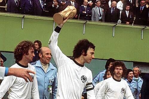 Weltmeister  1974: Paul Breitner (ganz rechts) schaut auf Franz Beckenbauer mit dem Pokal.