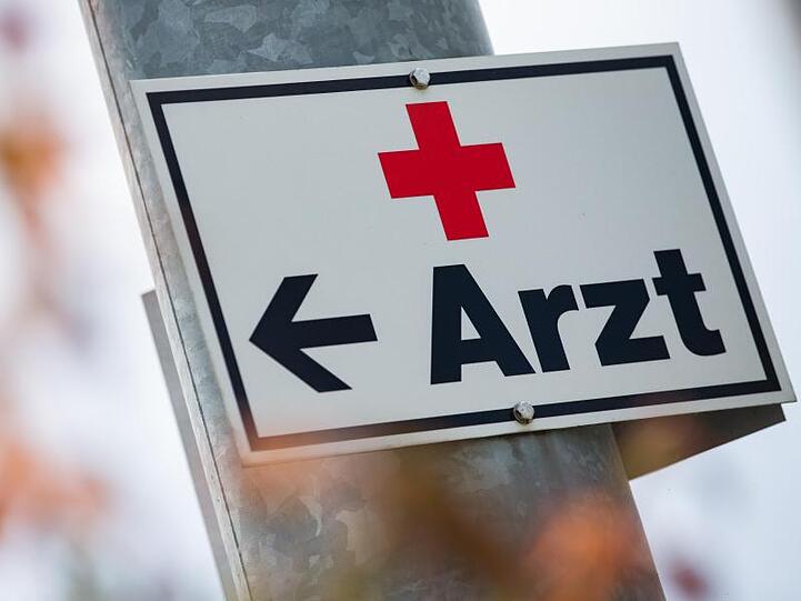 Ein Schild mit der Aufschrift "Arzt" hängt an einer Straßenlaterne. Foto: Tom Weller/dpa/Archiv/Symbolbild