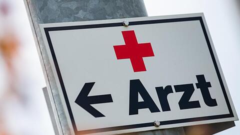 Ein Schild mit der Aufschrift "Arzt" hängt an einer Straßenlaterne. Foto: Tom Weller/dpa/Archiv/Symbolbild