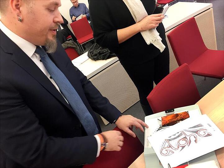 Polizeioberkommissar Jürgen Prichta hält bei der Verhandlung am Bayerischen Verwaltungsgerichthof die Entwürfe für sein geplantes Tattoo in den Händen.