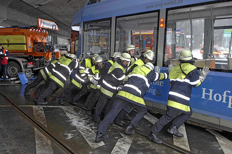 Helfer der Münchner Feuerwehr bringen die entgleiste Tram zurück auf die Schienen.