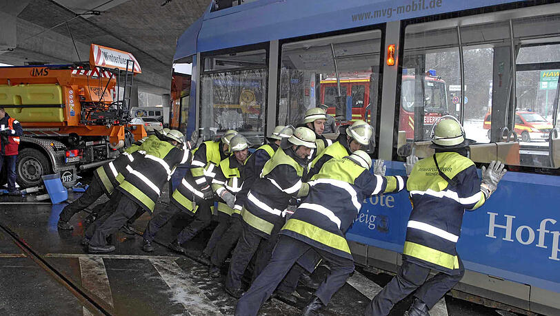 Helfer der Münchner Feuerwehr bringen die entgleiste Tram zurück auf die Schienen. Helfer der Münchner Feuerwehr bringen die entgleiste Tram zurück auf die Schienen.