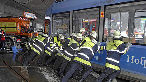 Helfer der Münchner Feuerwehr bringen die entgleiste Tram zurück auf die Schienen.