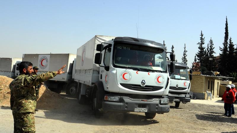 Ein syrischer Soldat weist Lastwagen des Syrisch-Arabischen Roten Halbmondes mit Hilfsgütern in Richtung eines umkämpften Gebiets (Archiv). Ein syrischer Soldat weist Lastwagen des Syrisch-Arabischen Roten Halbmondes mit Hilfsgütern in Richtung eines umkämpften Gebiets (Archiv).