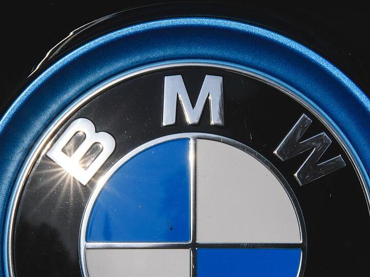 Die Sonne spiegelt sich in einem Logo des Autoherstellers BMW. Foto: Sebastian Gollnow/dpa/Archivbild
