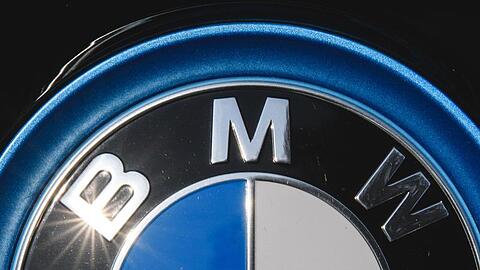 Die Sonne spiegelt sich in einem Logo des Autoherstellers BMW. Foto: Sebastian Gollnow/dpa/Archivbild