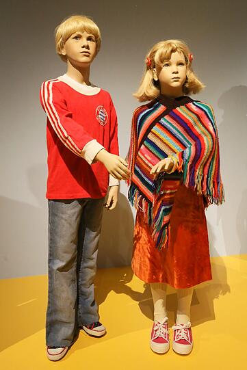 &bdquo;Diesen bunten Poncho hat mir meine Mutter nach einer Anleitung aus der ,Brigitte&rsquo; gestrickt&ldquo;, erzählt Ausstellungsmacherin Isabella Belting. Er war ihr &bdquo;Lieblingsteil&ldquo;, das sie an ihre Kinder weitergab, und von dem sie sich bis heute nicht trennen konnte. Das FC-Bayern-Shirt daneben hat eine ähnliche Geschichte: Es gehört Isabella Beltings Mann.