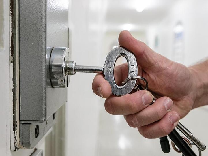 Ein Justizvollzugsbeamter mit einem Schlüssel an der Tür in einer Justizvollzugsanstalt. Foto: Markus Scholz/Archiv