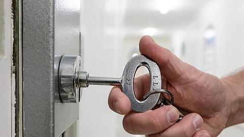 Ein Justizvollzugsbeamter mit einem Schlüssel an der Tür in einer Justizvollzugsanstalt. Foto: Markus Scholz/Archiv