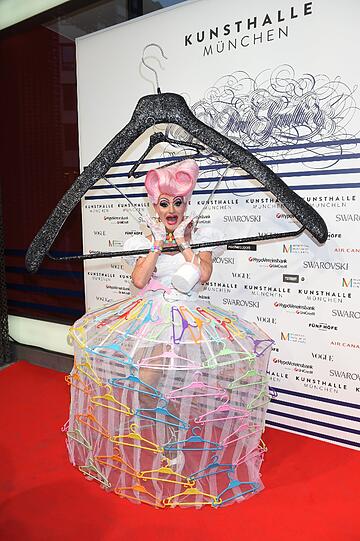 Eine Dragqueen als lebender Kleiderbügel