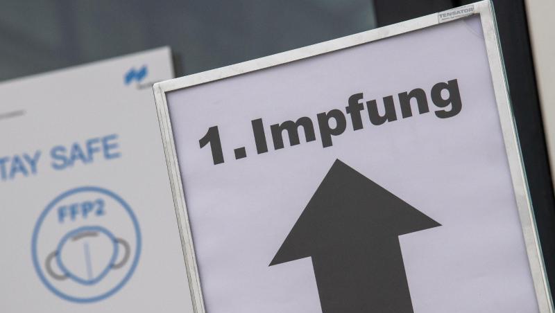 Ein Schild auf einem Messegelände weist den Weg zu einem Impfzentrum.