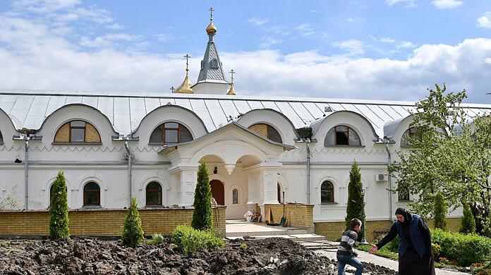 In Adamiwka hilft die orthodoxe Schwester Evdokia (r) einem Jungen namens Maxim aus einem durch russischen Beschuss entstandenen Krater.