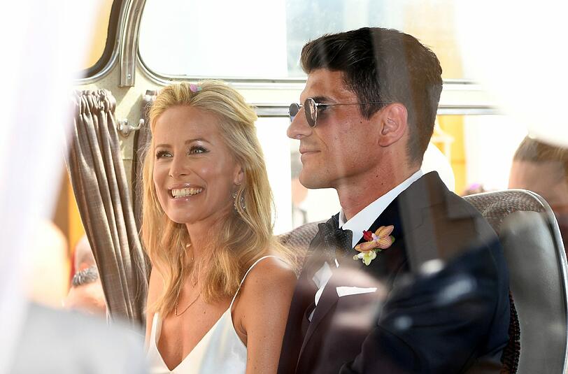 Mario und Carina: Er im dunkelblauen Anzug und mit Sonnenbrille. Sie in Weiß und Blumen im Haar.