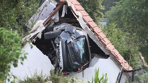 Das Auto liegt nach einem kurzen Flug seitlich in der Mauer einer Scheune.