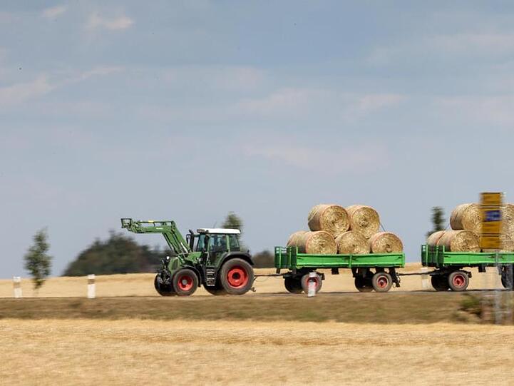 Ein Traktor zieht zwei mit Strohballen beladene Hänger. Foto: Jan Woitas/dpa-Zentralbild/ZB/Symbolbild