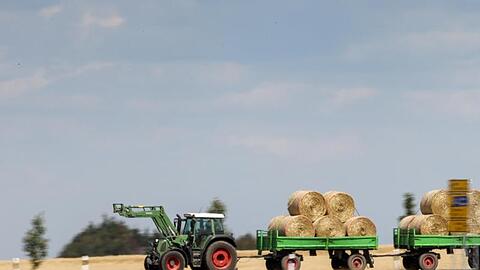 Ein Traktor zieht zwei mit Strohballen beladene Hänger. Foto: Jan Woitas/dpa-Zentralbild/ZB/Symbolbild
