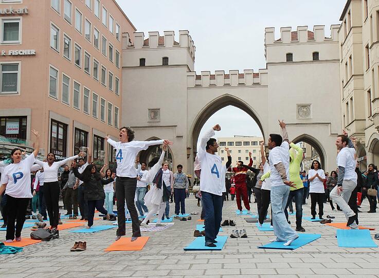 Hopsen und Dehnen in der Fußgängerzone: Am Stachus haben sich Yoga-Fans zu einem Flashmob unter freiem Himmel verabredet. Die Bilder.