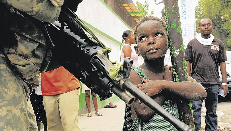 Sie tragen zwar Waffen, aber im Moment sind sie die Retter: Ein kleiner Bub schaut hoffnungsvoll zu einem Soldaten der 82. US-Luftlandedivision auf.Foto: Polaris Sie tragen zwar Waffen, aber im Moment sind sie die Retter: Ein kleiner Bub schaut hoffnungsvoll zu einem Soldaten der 82. US-Luftlandedivision auf.Foto: Polaris
