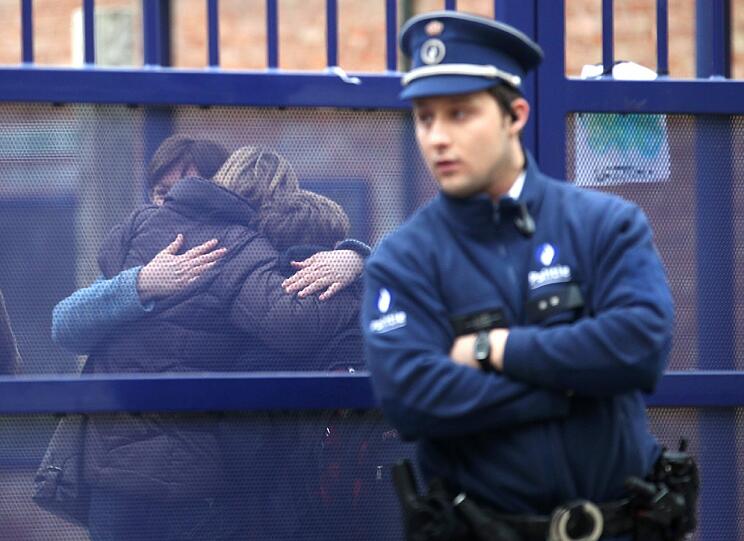 Vor einer Schule in Belgien fallen sich Angehörige der Opfer des Todesbusses in die Arme.