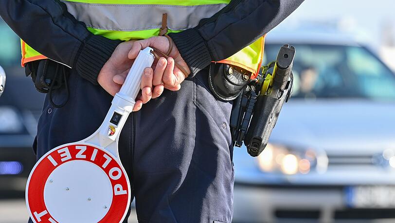 Ein Polizeibeamter hält eine Winkerkelle in den Händen.