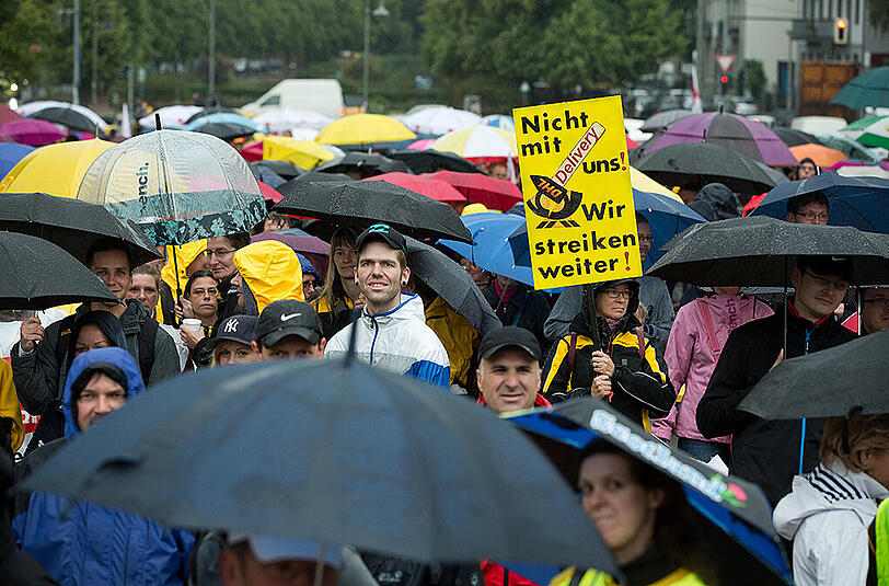Bei einer Streikversammlung der Deutschen Post in Berlin wird ein Schild mit der Aufschrift "Nicht mit uns! Wir streiken weiter!" in die Höhe gehalten.