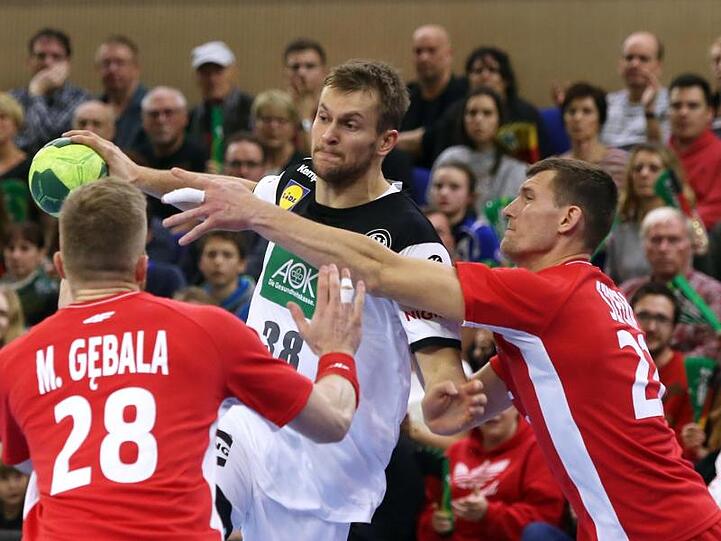 Deutschlands Fabian Böhm (M) setzt sich im WM-Test gegen Polen gegen zwei Gegenspieler durch.