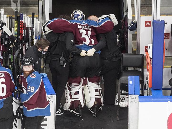 Dem verletzten Torhüter Philipp Grubauer (M) von den Colorado Avalanche wird in die Umkleidekabine geholfen.