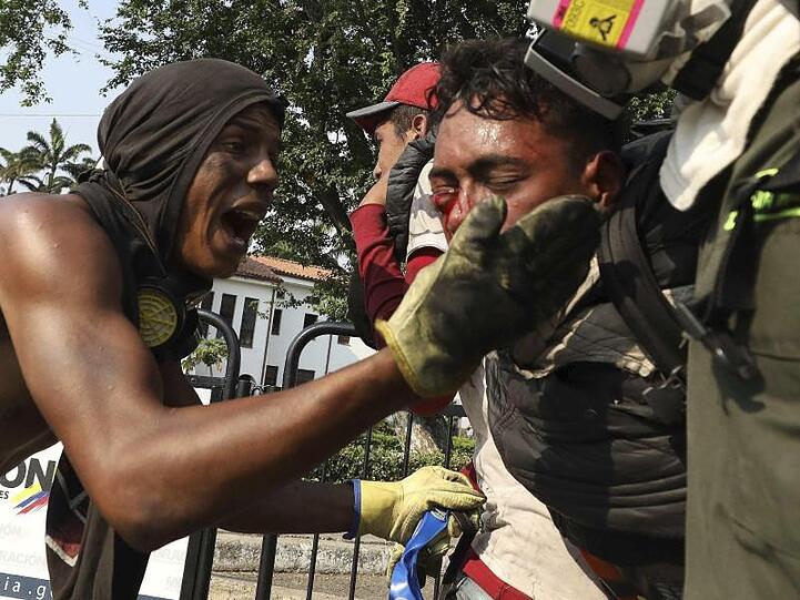 Dramatische Szene auf der Grenzbrücke zu Kolumbien: Ein junger Mann, der bei erneuten Zusammenstößen verletzt wurde, wird von einem weiteren Demonstranten angesprochen.