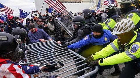 Trump-Anhänger versuchen am 6. Januar, am Kapitol eine Absperrung zu durchbrechen. Polizisten halten dagegen.