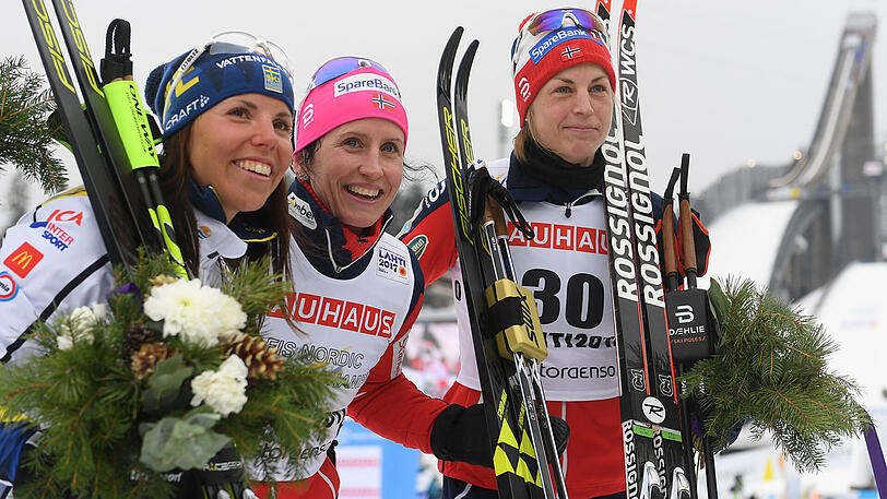 Rekordsiegerin Marit Björgen aus Norwegen (Mitte) bei der Flower Ceremony - mit der Zweitplatzierten Charlotte Kalla aus Schweden (links) und Astrid Uhrenholdt Jacobsen aus Norwegen.
