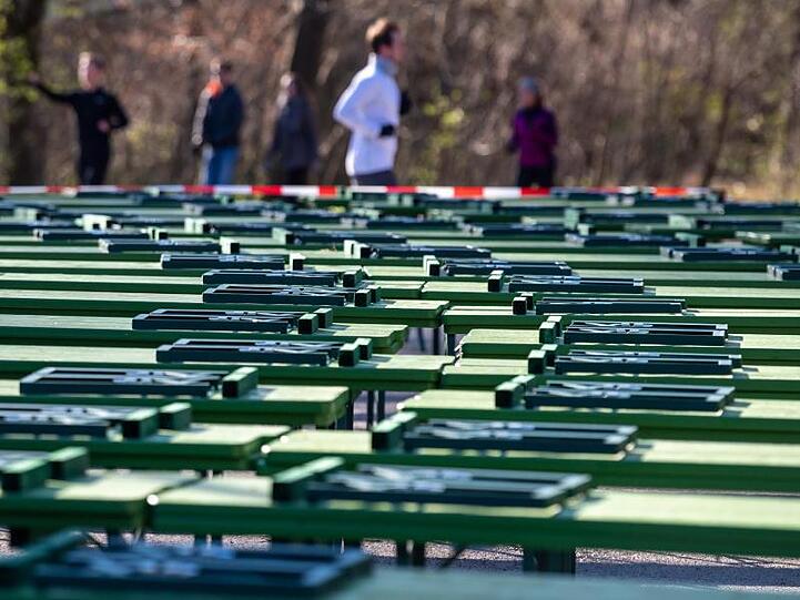 Jogger laufen im Englischen Garten durch den gesperrten Biergarten am chinesischen Turm. Foto: Peter Kneffel/dpa/Archivbild