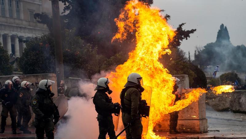 Griechische Bereitschaftspolizisten stehen vor einer Feuerwand, verursacht durch einen Molotow-Cocktail.