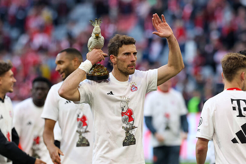 Ein Bayern-Profi feiert mit dem Team-Maskottchen Kakadu in der Hand und Meistershirt auf dem Rasen der Allianz Arena die 35. Meisterschaft nach dem 4:2 gegen Stuttgart.