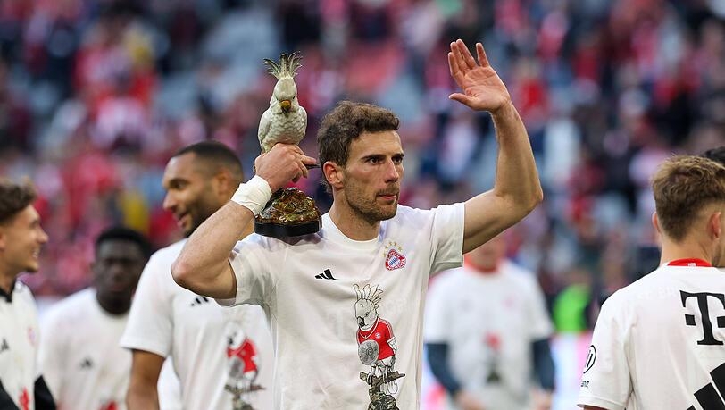 Ein Bayern-Profi feiert mit dem Team-Maskottchen Kakadu in der Hand und Meistershirt auf dem Rasen der Allianz Arena die 35. Meisterschaft nach dem 4:2 gegen Stuttgart.