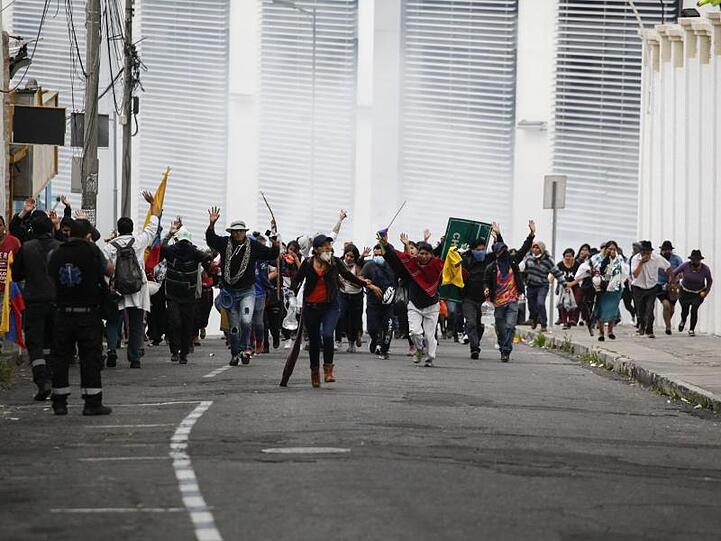 Teilnehmer einer Demonstration fliehen in Quito vor einer Wolke Tränengas.
