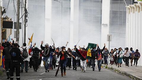 Teilnehmer einer Demonstration fliehen in Quito vor einer Wolke Tränengas.