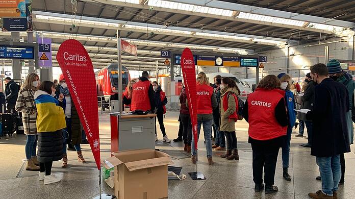 An einem provisorischen Stand in der Bahnhofshalle helfen die Mitarbeiter der Caritas weiter.