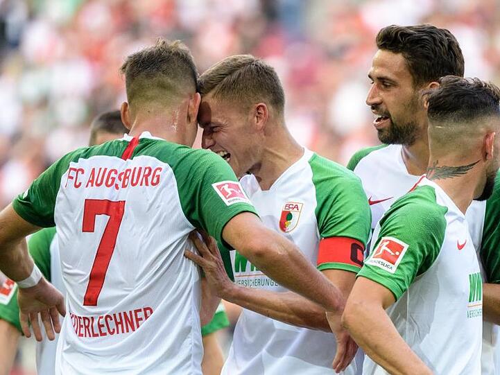 Augsburgs Torschütze Florian Niederlechner (l) und Alfred Finnbogason jubeln mit der Mannschaft über den Treffer zum 2:0.