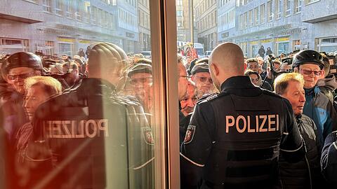 Polizisten sichern den Eingang der Sparkassenfiliale in Gelsenkirchen, vor der viele besorgte Kunde stehen und Informationen nach dem Einbruch in den Tresorraum verlangen.