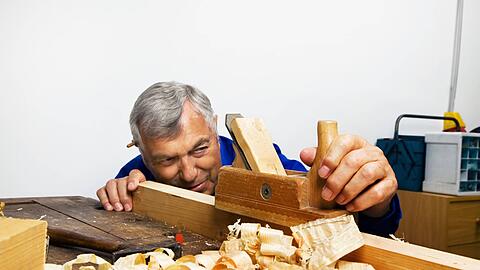 Ein Tischler mit einem Hobel in der Werkstatt. Menschen mit hoher Belastung h&auml;tten eine deutlich geringere Lebenserwartung, sagt DGB-Bayern-Chef Bernhard Stiedl.