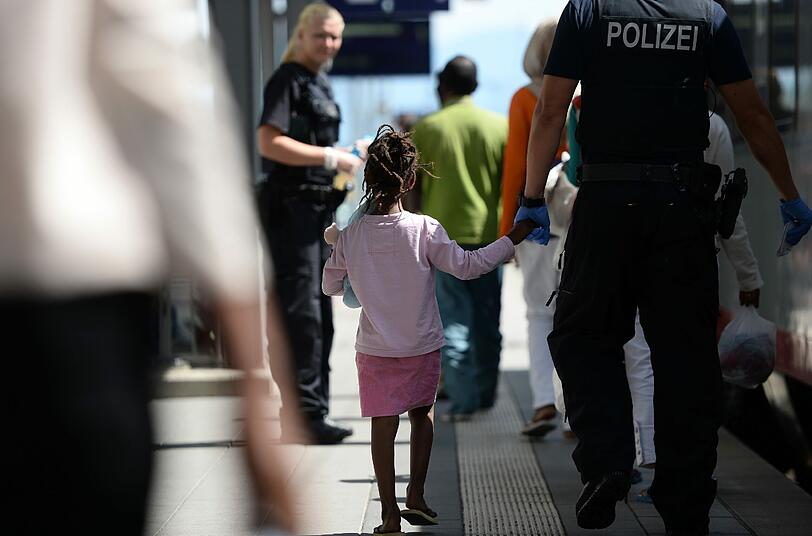 Kleine Geste, große Wirkung: Ein Polizist nimmt ein Flüchtlingsmädchen an die Hand.