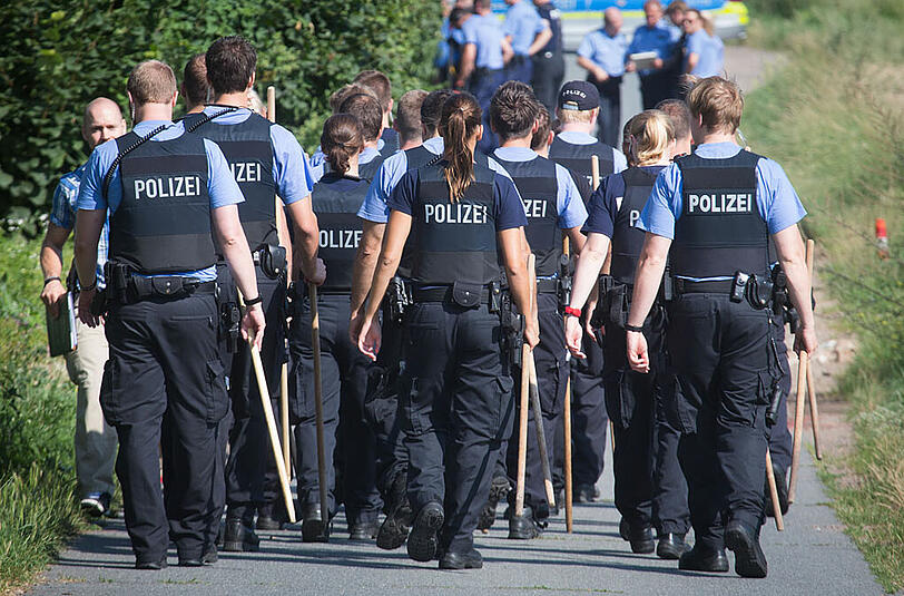 Polizisten durchkämmen am 24.07.2014 in Bischofsheim im Kreis Groß-Gerau (Hessen) ein Kornfeld in unmittelbarer Nähe des Tatorts, an dem am Abend zuvor ein Polizist erschossen wurde.