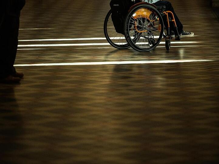 Ein Mann steht mit seinem Rollstuhl in einem Foyer. Foto: Andreas Arnold/Archivbild
