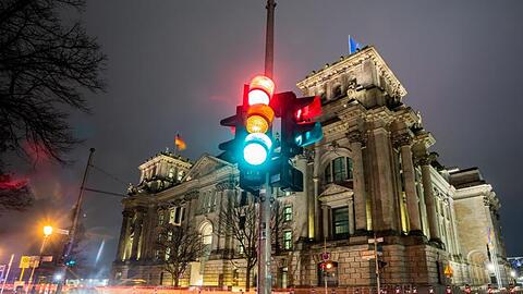 Vor dem Reichstagsgebäude in Berlin, dem Sitz des deutschen Bundestags, leuchtet eine Ampel - durch eine Langzeitbelichtung in allen drei Phasen.