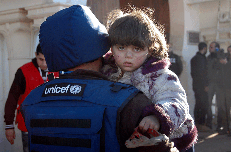 Ein Unicef-Mitarbeiter bringt ein Kind im syrischen Horms in Sicherheit.