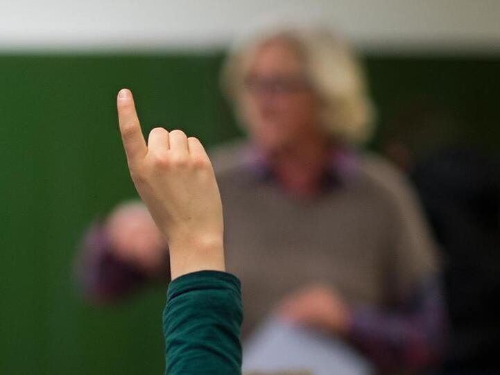 Ein Lehrer steht an der Tafel. Foto: Julian Stratenschulte/dpa/Archivbild